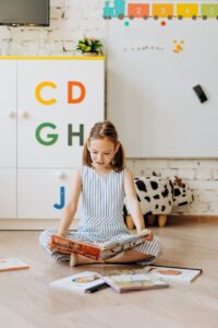 A Girl Sitting on the Floor Holding a Book